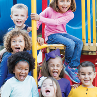 photo of a diverse group of seven elementary age children on school playground equipment
